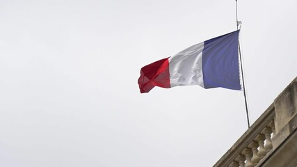 French flag waving in slow motion on a building