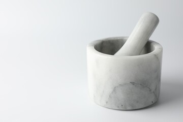 Marble mortar with pestle on white background, closeup. Space for text