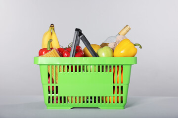 Fototapeta na wymiar Shopping basket with different food products on gray background