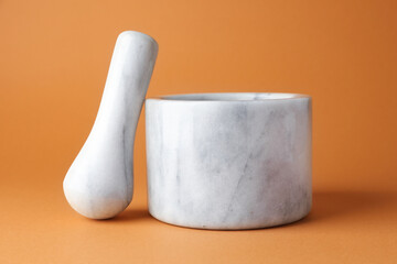 Marble mortar and pestle on light brown background, closeup