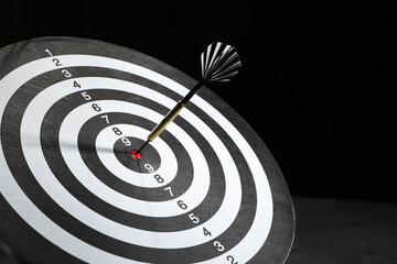 Targeting. Dart board with arrow on dark background, closeup