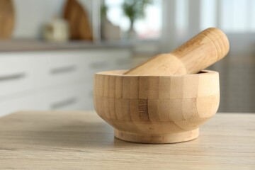 Mortar and pestle on wooden table in kitchen, closeup