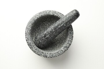 Stone mortar and pestle on white table, top view