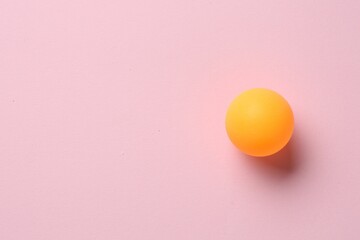 One ping pong ball on pink background, top view. Space for text