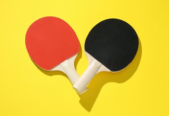 Ping pong rackets on yellow background, top view