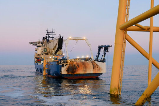 Offshore DP3 Cable Laying Vessel Deploying Subsea Cable Next To Substation Installation During Wind Farm Construction