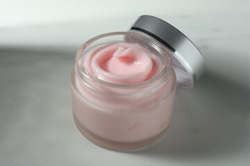 Jar of moisturizing body cream on white table, closeup