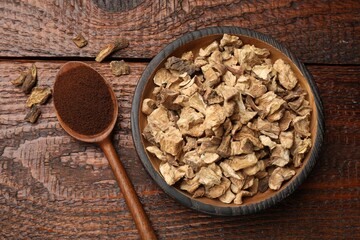 Pieces of dry chicory roots in bowl and spoon with powder on wooden table, flat lay