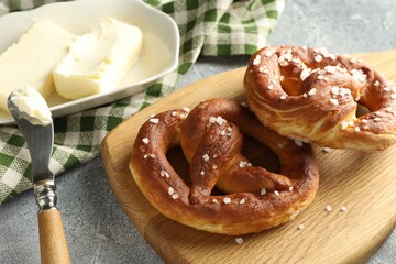 Tasty pretzels with salt and butter on light grey table, closeup