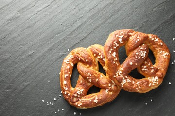 Tasty pretzels with salt on black table, flat lay. Space for text