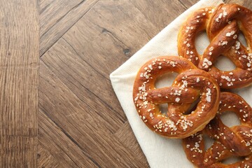 Tasty pretzels with salt on wooden table, flat lay. Space for text