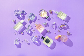 Flat lay composition with perfume bottles and lilac flowers on violet background