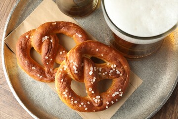 Tasty pretzels and beer on wooden table, top view