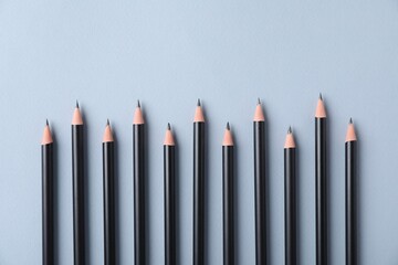 Many sharp graphite pencils on light grey background, flat lay. Space for text