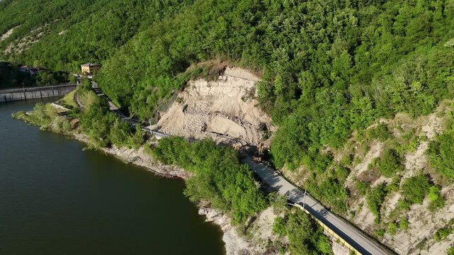 Terrain landslide due to spring heavy rains blocks provincial road 21 near Vernasca Mignano dam and basin with heavy machinery clearing debris, PC, Italy