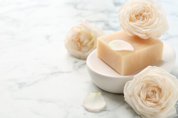Soap bar and flowers on white marble table, closeup. Space for text