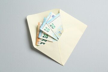 Money bonus. Envelope with euro banknotes on light grey background, top view