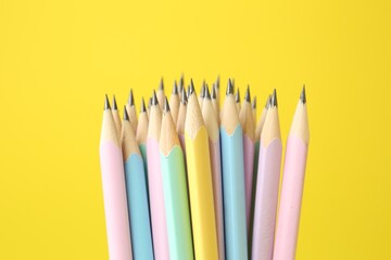 Many graphite pencils on yellow background, closeup