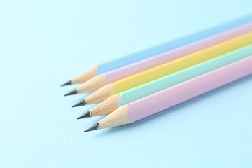 Many graphite pencils on light blue background, closeup. Space for text