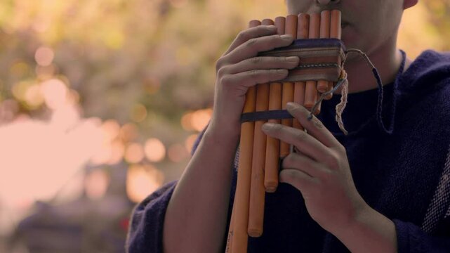 Man playing traditional Andean pan flute outdoors 