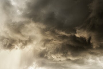 Obraz premium Dramatic cloudy sky with dark storm clouds and rays of sunlight breaking through the ominous overcast weather creating a moody atmospheric scene