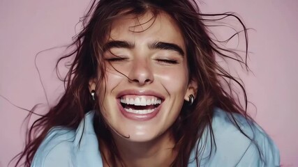 Radiant woman with windswept hair, caught in a joyful, unrestrained laugh against a soft pink backdrop. A vibrant portrait of pure happiness