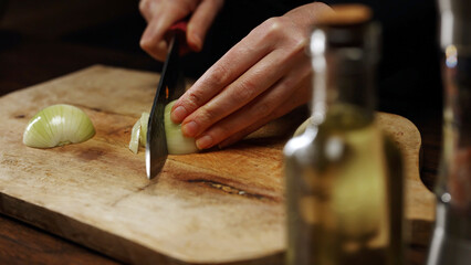 Female Chef Slicing Onion on Wooden Cutting Board.