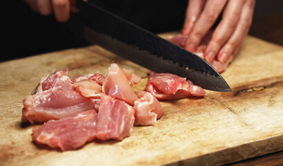 Female Chef Cutting Chicken Thighs with Knife.
