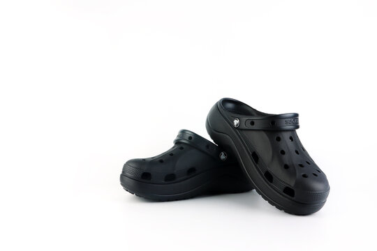 nice rubber black Crocs shoes are displayed on white floor with stones on background display wearing crocs lifestyle sandals at shoes store during opening new model crocs footwear diy design contest