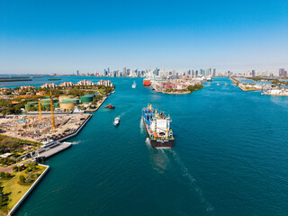 Obraz premium Miami, Florida, USA - March 20, 2025: Miami port. Container ship. Cargo Warnow Whale Limassol ship with container in Miami aerial. Freight container on cargo vessel. Cargo ship vessel. aerial view