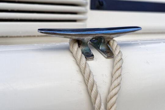 White ropes and silver cleats detail on white yacht rigging