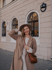 Beautiful young woman in hat and coat walking around european city