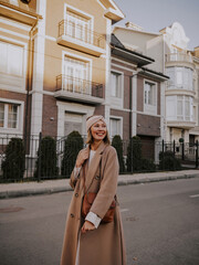 Beautiful young woman in coat walking around european city
