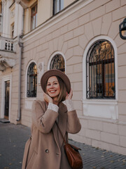 Beautiful young woman in hat and coat walking around european city