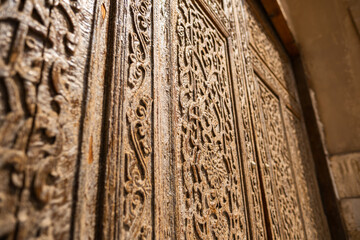 Traditional Islamic wooden door with intricate carved floral and geometric patterns close up, antique handcrafted design detail in historic architecture of Central Asia, cultural heritage texture