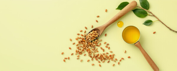 Fototapeta premium Peanut seeds and oil in wooden spoons with green leaves on light background, natural and fresh