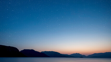 a a movement of stars in the night sky with the view of mountains..