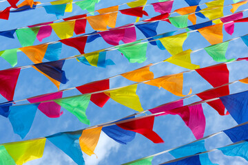 Multicolored triangular flags are fluttering in the wind against the sky