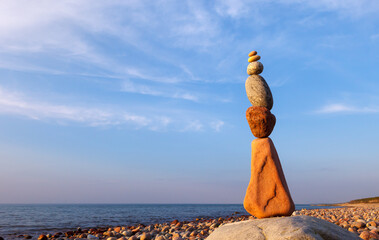 Rock zen pyramid of colorful pebbles on a beach on the background of the sea.