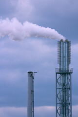 Tall exhaust towers releasing vaporous plumes under overcast heavens, ecological decline and human...