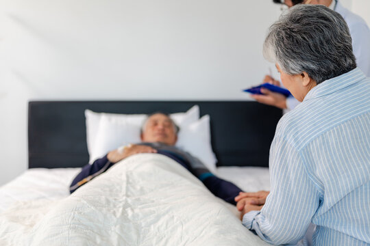 scene of bedridden patient, back view of wife illness's relative holding hand elderly hopeless senior male with infectious disease, concept of nursing home care or medical treatment in hospital ward