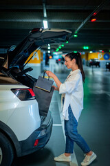 Woman parking in car park and packing into her car's trunk