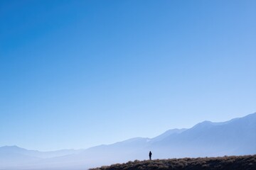 silhouette of solitary figure standing gracefully against backdrop of majestic mountains