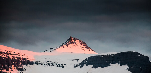 Golden hour light over snow-capped peaks in Faskrudsfjordur, East Iceland...