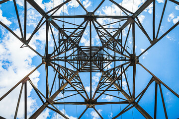 Abstract geometric pattern of an electricity pylon viewed from below against a bright blue sky, great for industrial or abstract backgrounds