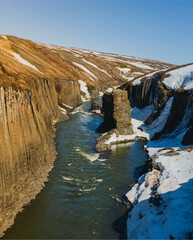 Studlagil Canyon in East Iceland with snow patches and basalt cliffs...