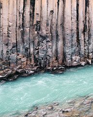 Turquoise glacial river flows past basalt cliffs in Studlagil Canyon, Iceland...