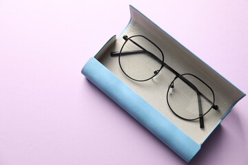 Case with stylish glasses on violet background, top view. Space for text