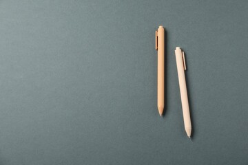 Stylish pens on grey background, above view. Space for text