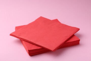 Stack of red handkerchiefs on pink background, closeup